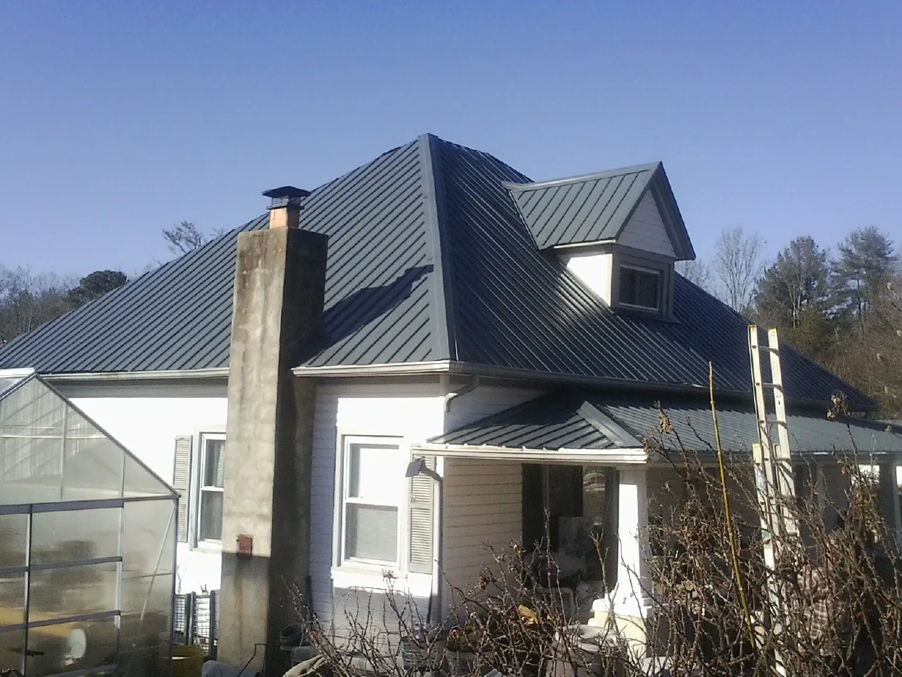 Dark blue standing seam metal roof on a white farmhouse with dormer — Slate & Tile Roof Repair by Roofing Brothers in Covesville