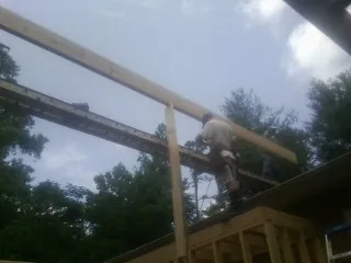 Carpenter setting a ridge beam over a new addition frame — Ice Dam Removal by Roofing Brothers in Covesville