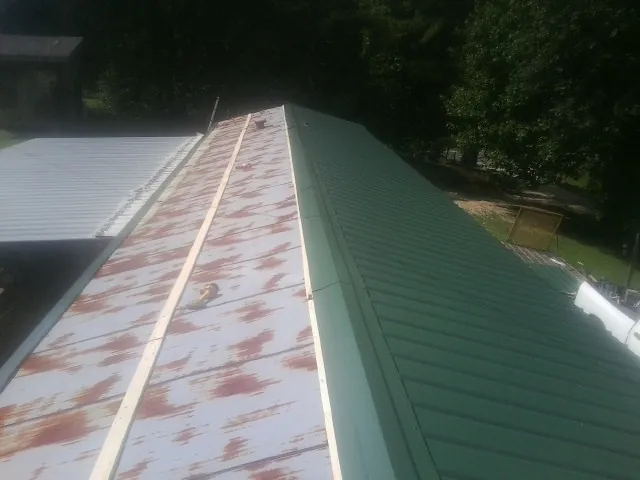 Old rusted panels beside newly installed green metal roofing — Wind Damage Roof Repair by Roofing Brothers in Covesville