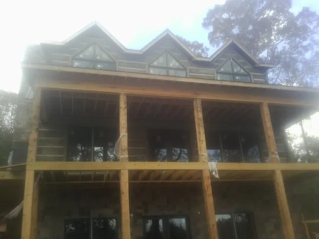 Dormers and porch framing on a large log home under construction — Roof Coating work by our crew in Covesville