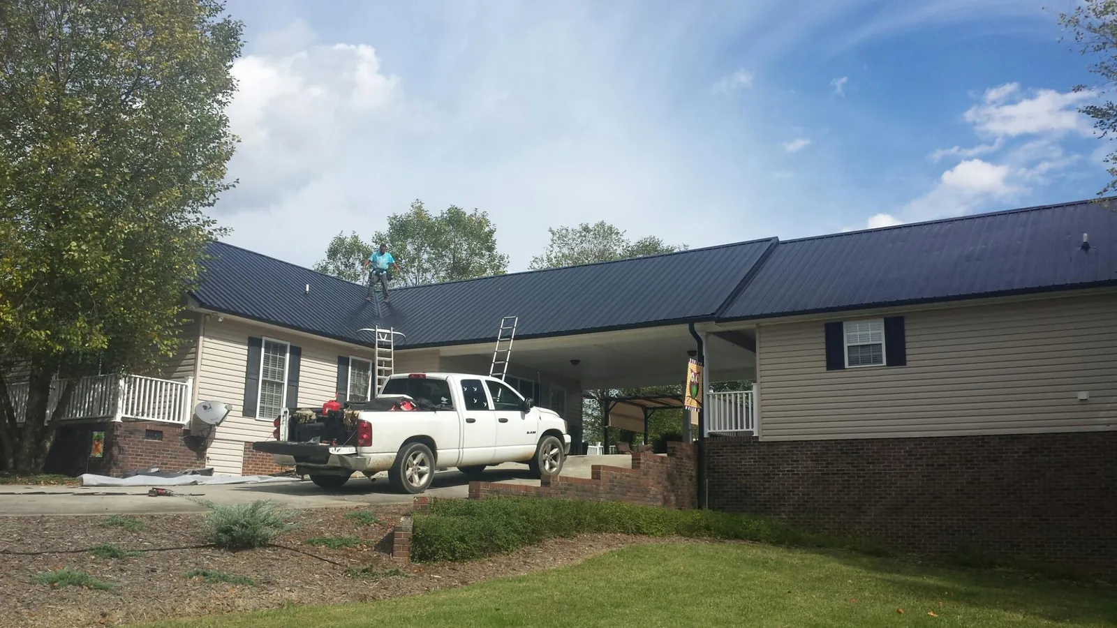 Black metal roof over a home and attached breezeway with ladders set in Covesville