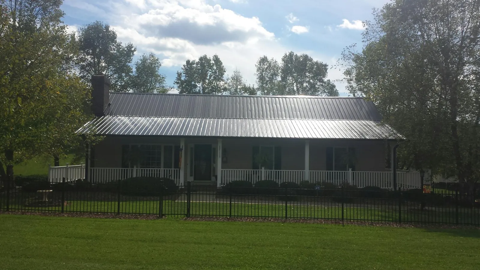 Gray metal roof on a brick ranch with a full width front porch — Gutter Guard Installation work by our crew in Covesville