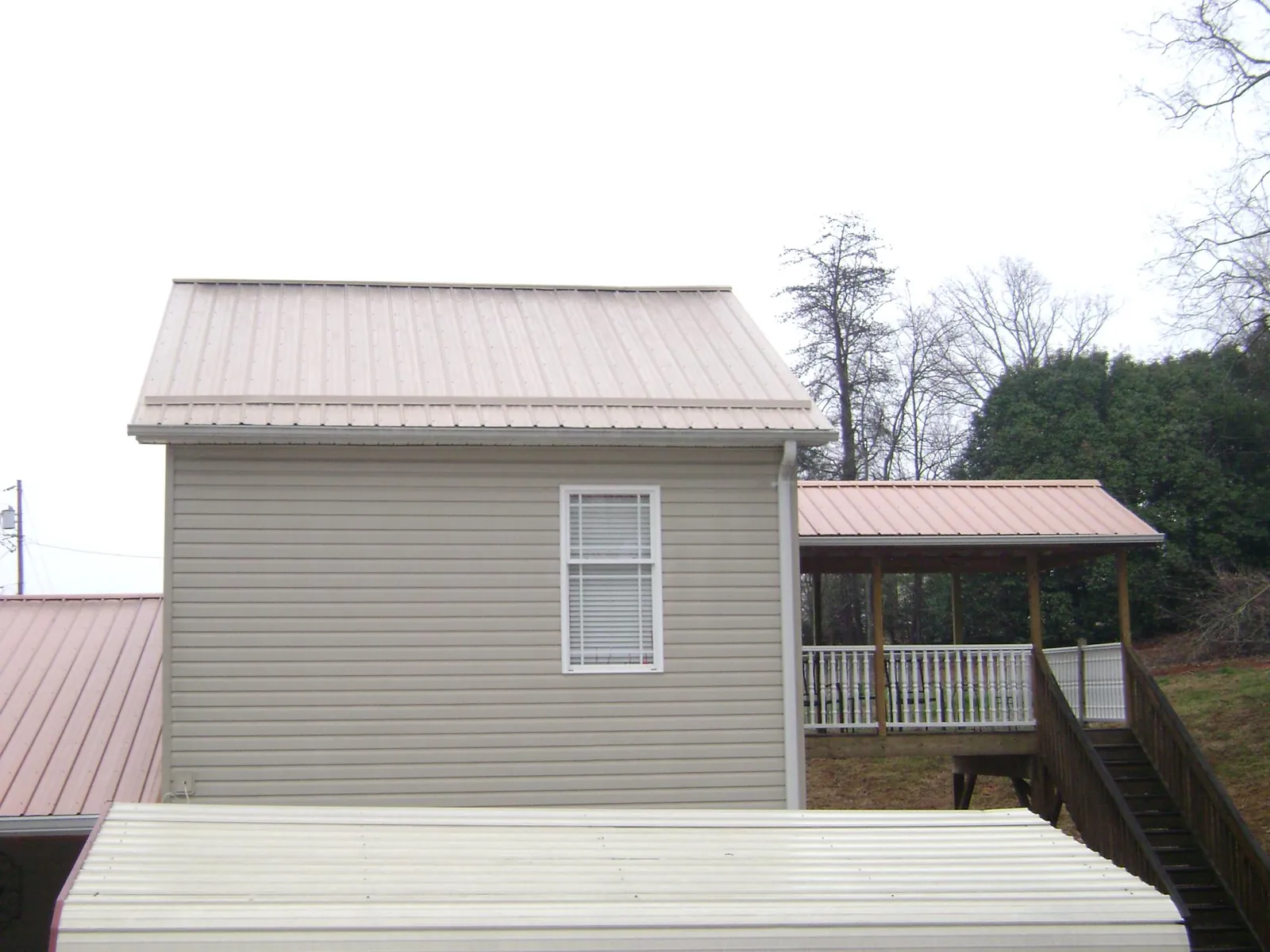 Tan metal roofs on a two story addition and attached porch, from a Roof Replacement job in Covesville