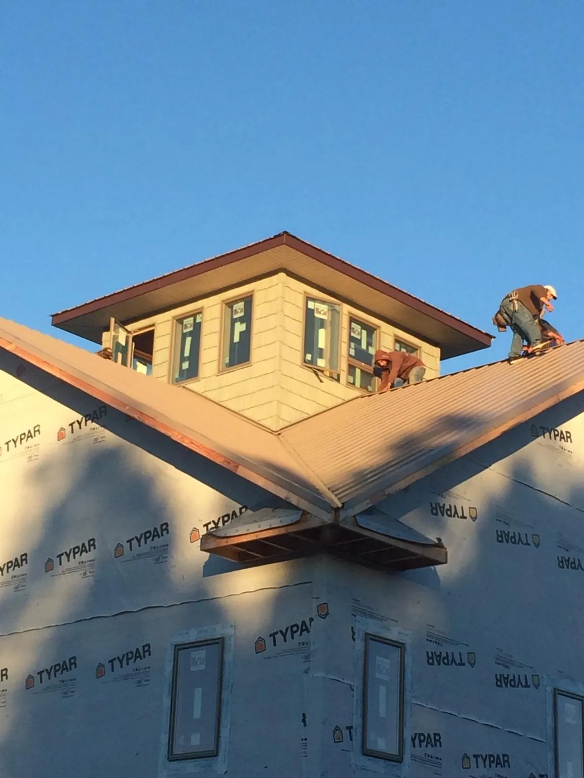 Roofers working around a rooftop cupola on a new metal roof at sunset — Roof Waterproofing in Covesville by Roofing Brothers